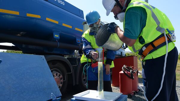 Сотрудники АЗС берут пробу бензина во время приемки бензовоза